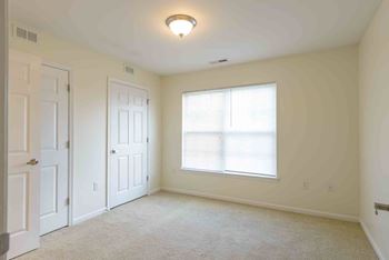 A room with a window and a carpeted floor.